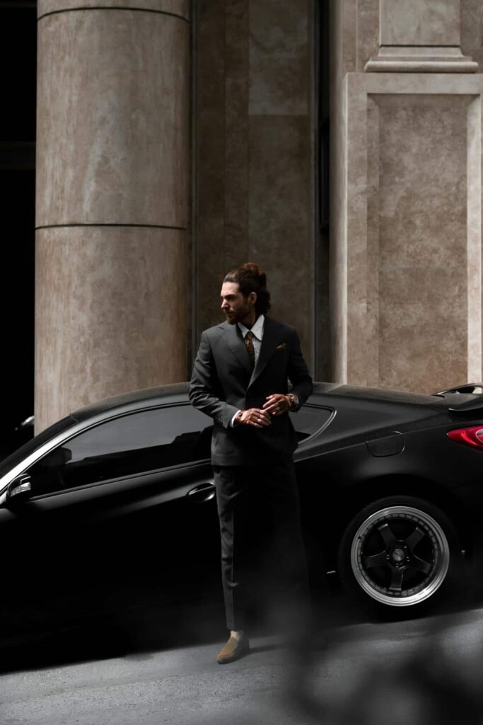 Man in suit beside luxury car.